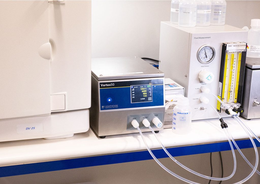 A Vertex50 liquid particle counter connected to fluid tubes within a laboratory setting