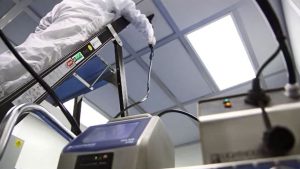 Photograph of a gowned cleanroom worker using the SOLAIR airborne particle counter in combination with the ScanAir attachment.