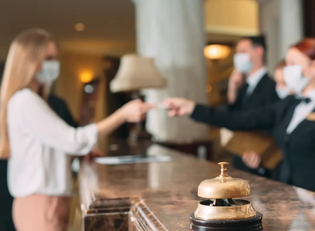 A shallow photograph of a hotel lobby interior, where the desk clerk is handing a guest their key card.