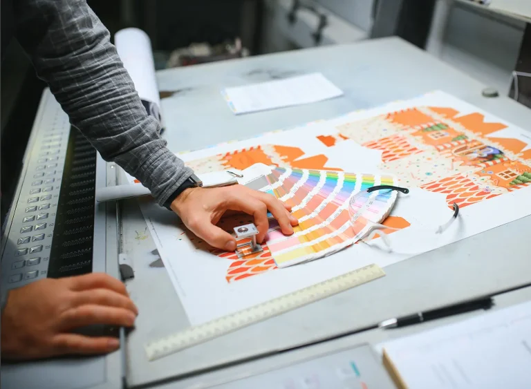 A photograph of a print shop professional using color swatches on an angled table.