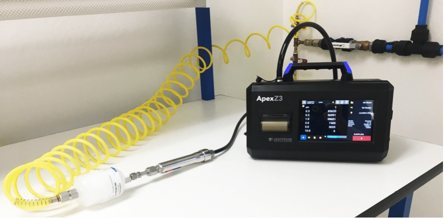 A photograph of an ApexZ3 portable airborn particle counter configured for gas sampling within a cleanroom environment.